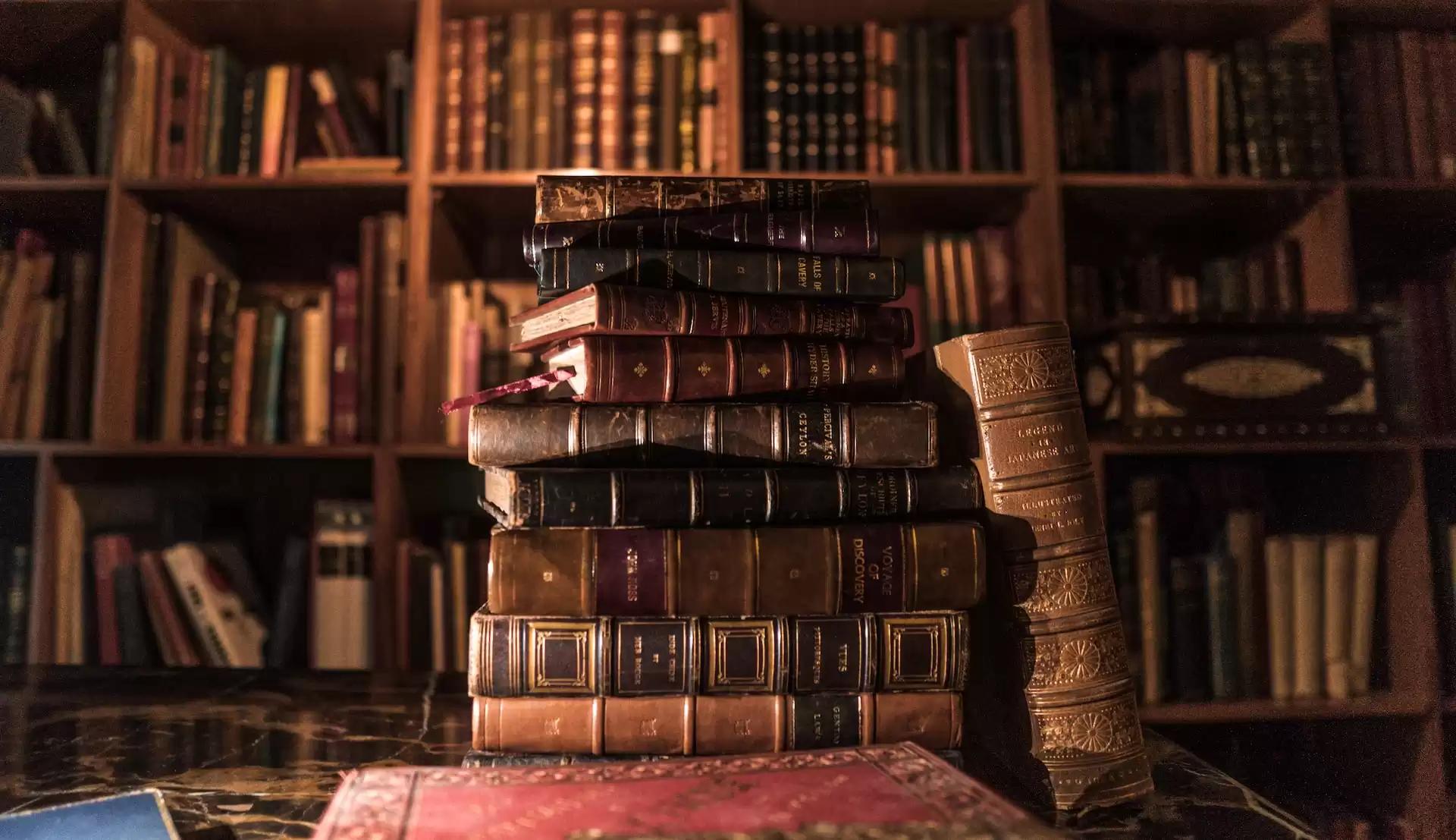 stack of old books on a desk inside someone’s personal library